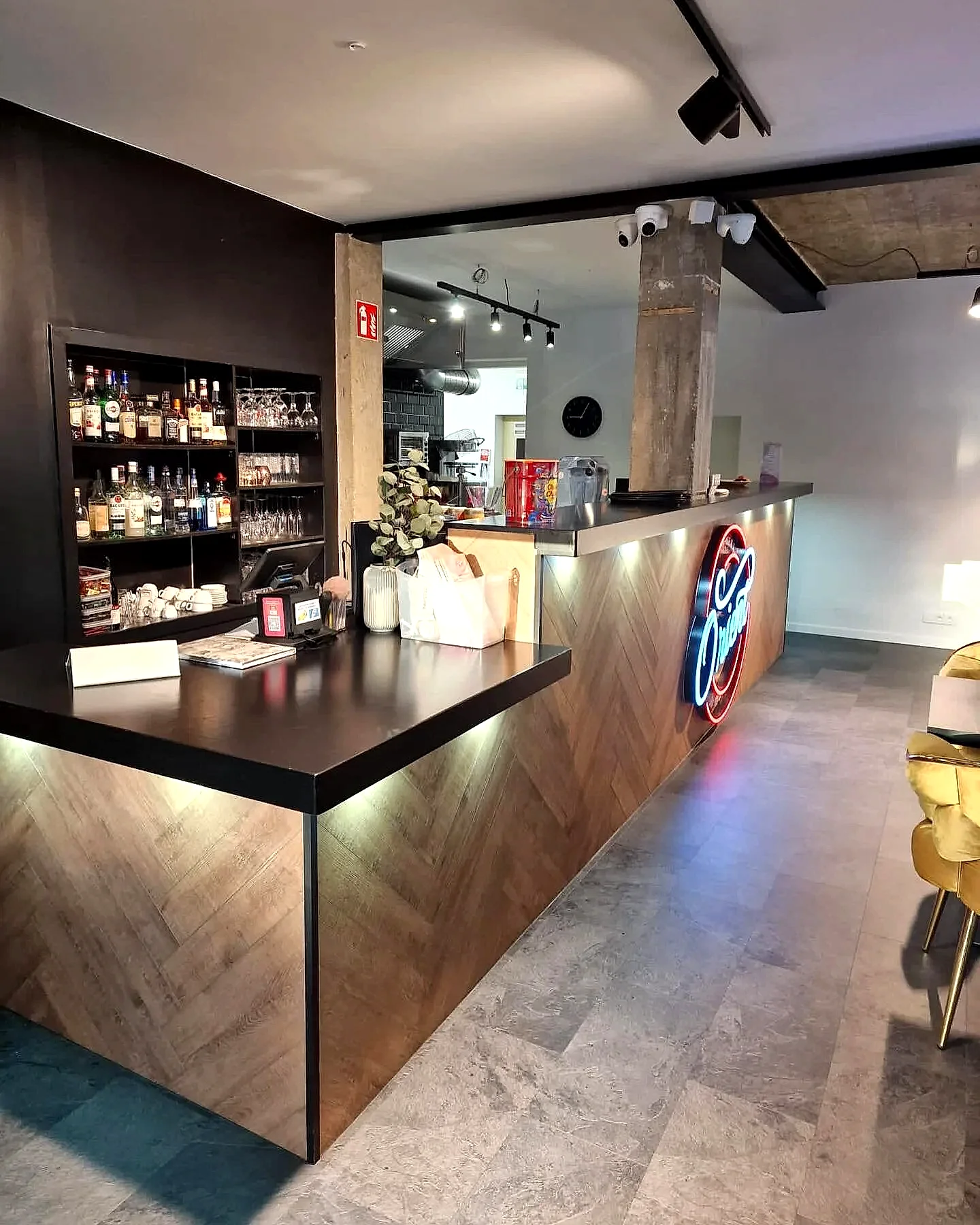 De bar van Orient Herent, met notenhouten lamellen en het neon Orient-logo